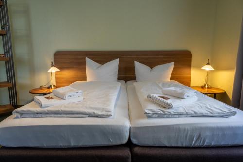 two beds with white pillows and books on them at Spielzeughotel Sonneberg in Sonneberg