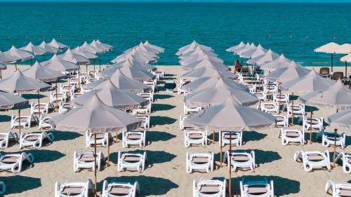 a group of white chairs and umbrellas on a beach at Aks Hotel in Durrës