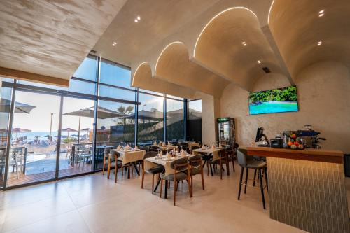 a dining room with tables and chairs and windows at Aks Hotel in Durrës