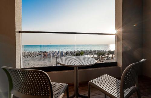 a table and chairs in a room with a view of the beach at Aks Hotel in Durrës