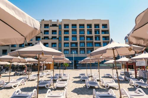 a beach with chairs and umbrellas and a building at Aks Hotel in Durrës