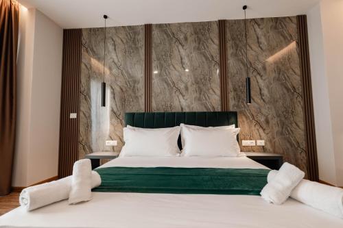 a bedroom with a large bed with a green headboard at Aks Hotel in Durrës