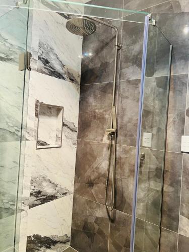 a shower with a glass door in a bathroom at Modern One Bedroom Unit with Private Entrance Near Hunua Falls in Hunua