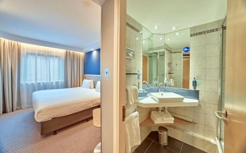 a hotel room with a bed and a bathroom at Holiday Inn Express London Stratford by IHG in London