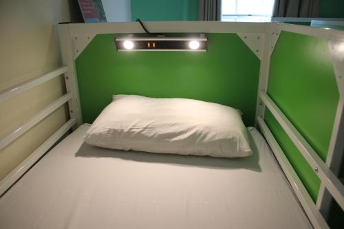 a bed with a white pillow in a green room at Safestay Edinburgh Cowgate in Edinburgh