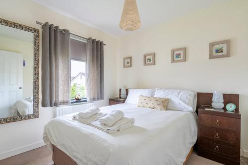ein Schlafzimmer mit einem weißen Bett mit Handtüchern darauf in der Unterkunft 3-Bed Portballintrae Home | Wi-Fi, Garden, Parking in Portballintrae