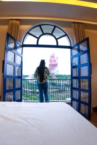 a woman standing on a balcony looking out of a window at Aarambh By The Sky Imperial, Nathdwara in Nāthdwāra