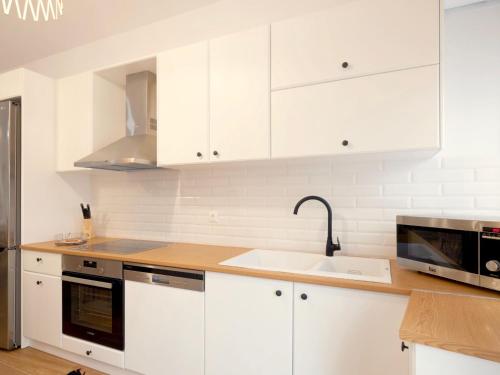 a kitchen with white cabinets and a sink and a microwave at Villa Sky in Skaleta