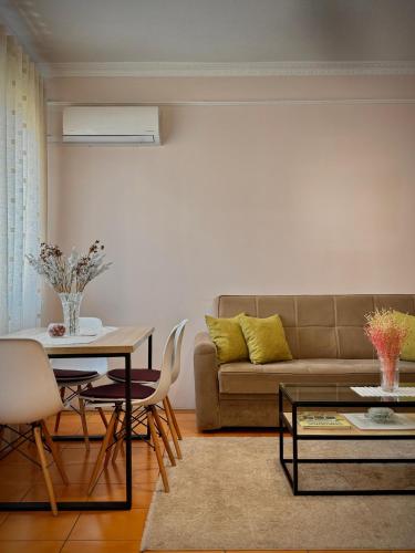 a living room with a couch and a table and chairs at All Seasons Apartments - Free Parking & City Center in Shkodër