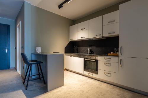 a kitchen with white cabinets and a chair in it at Downtown Apartments in Pristina