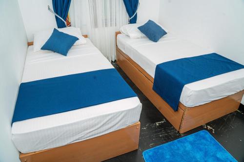 two beds in a small room with blue pillows at Coastal Heaven Villa in Trincomalee