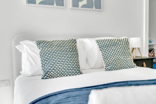 a white bed with two pillows on top of it at The Van Gogh Loft - By Raymond Properties in New Malden