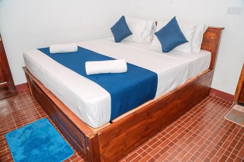 a bed with blue and white sheets and blue pillows at Coastal Heaven Villa in Trincomalee