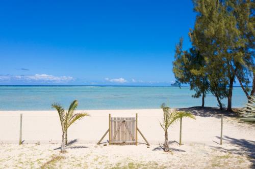 a beach with palm trees and a gate on it at Villa Philibert in Riambel