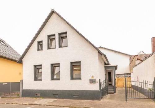 a white house with black windows on a street at Ein Familie Haus in Zentrale Lage in Dreieich