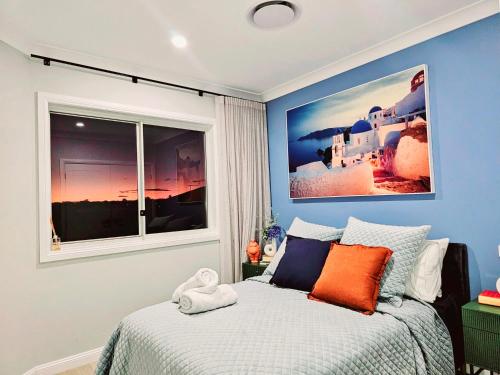 a bedroom with a bed with blue walls and a window at Luxury Hampton House with Heated pool in Narellan