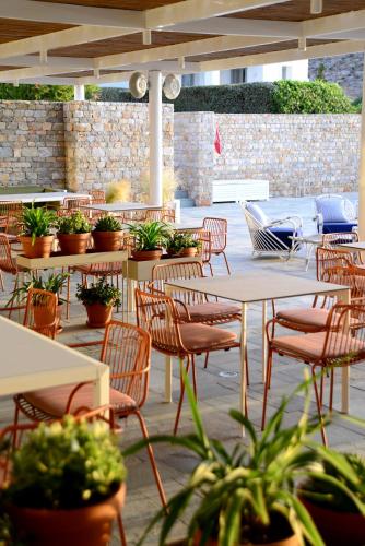 a patio with tables and chairs and potted plants at ANEMI Folegandros in Karavostasi