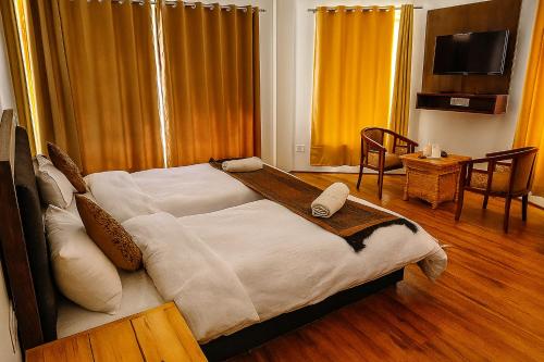 a bedroom with a large bed with white sheets at Hotel Grand Nubra in Deskit