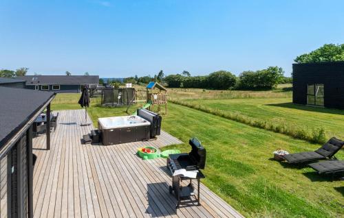 a deck with a hot tub and chairs on a lawn at Beautiful Home In Børkop With Sauna in Børkop