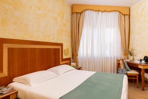 a bedroom with a bed and a desk and a window at Hotel & Residence Venezia 2000 in Venice-Lido