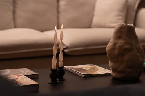 two candles sitting on a table with a vase at The Honest Hotel & Apartments in Seville