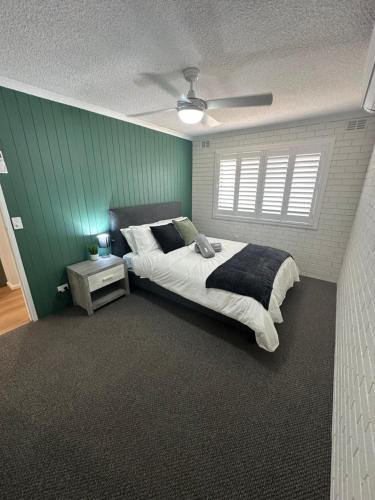 a bedroom with a large bed and a green wall at Central Cullen Wagga Apartments in Wagga Wagga