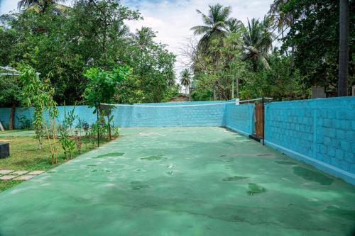 a tennis court in front of a blue fence at Coastal Heaven Villa in Trincomalee