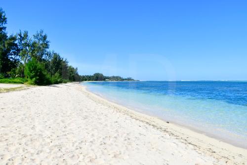 a beach with white sand and blue water at Villa Philibert in Riambel