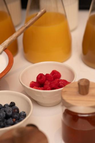 a bowl of raspberries and blueberries on a table at The Honest Hotel & Apartments in Seville