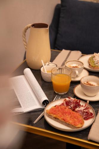 a table with plates of food and a plate of pizza at The Honest Hotel & Apartments in Seville