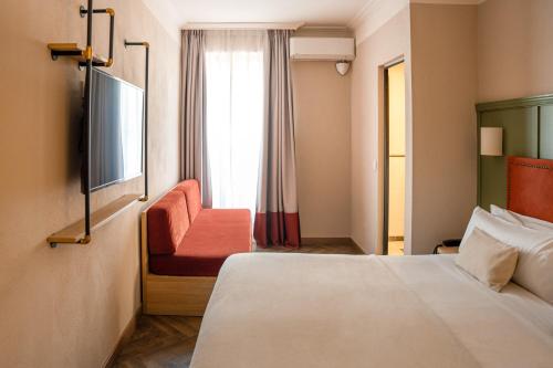 a hotel room with a bed and a chair and a window at The Honest Hotel & Apartments in Seville