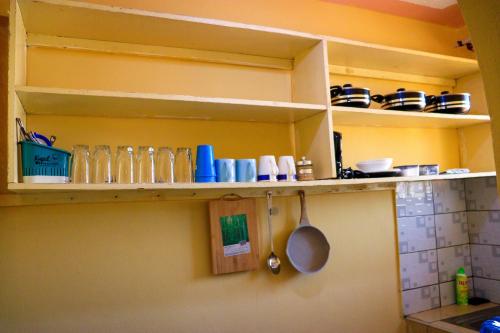 a kitchen shelf with dishes and utensils on it at Khalisee homes studio apartment 3 in Voi