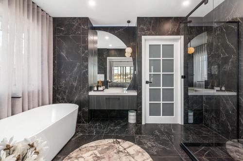 a bathroom with a tub and a sink at Luxury Hampton House with Heated pool in Narellan