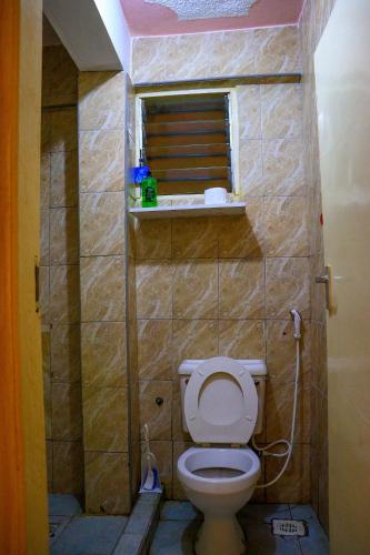a small bathroom with a toilet and a window at Khalisee homes studio apartment 3 in Voi