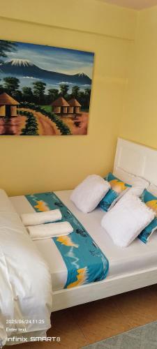 two beds in a room with a painting on the wall at Khalisee homes studio apartment 3 in Voi