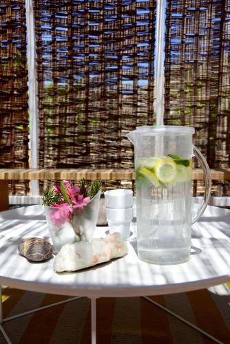 a table with a pitcher of water and some flowers at ANEMI Folegandros in Karavostasi