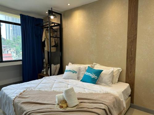 a bedroom with a bed with blue and white pillows at Homigo - PWTC in Kuala Lumpur