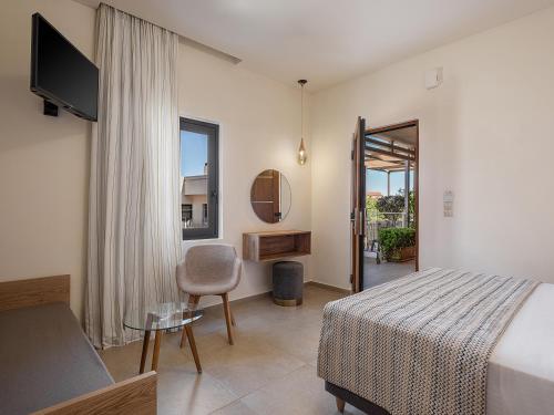 a bedroom with a bed and a chair and a television at Casa D'Irene Deluxe Hotel in Falasarna