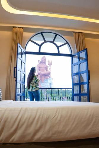 a woman standing on a bed in front of a window at Aarambh By The Sky Imperial, Nathdwara in Nāthdwāra