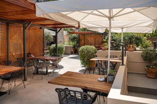 an outdoor patio with tables and chairs and an umbrella at Casa D'Irene Deluxe Hotel in Falasarna