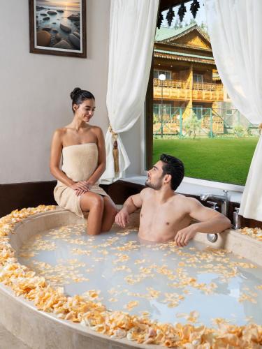 a man and woman sitting in a bath tub with a cake at The Khyber Himalayan Resort & Spa in Gulmarg