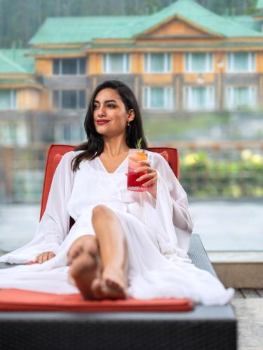 a woman sitting in a chair holding a drink at The Khyber Himalayan Resort & Spa in Gulmarg