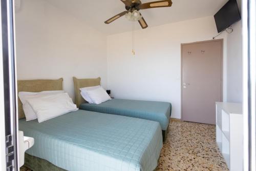 two beds in a room with a ceiling fan at Family House in Lakones in Paleokastritsa