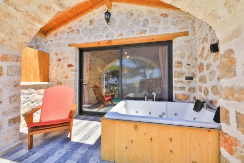 a bathroom with a tub and a chair and a window at Spacious 2BR Stone Villa with Pool & BBQ in Kalkan