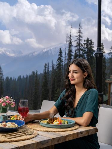 a woman sitting at a table with a plate of food at The Khyber Himalayan Resort & Spa in Gulmarg