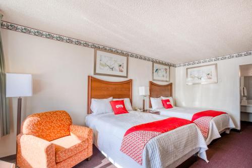 a hotel room with two beds and a chair at Travelers Inn By OYO, Templeton VA in Petersburg