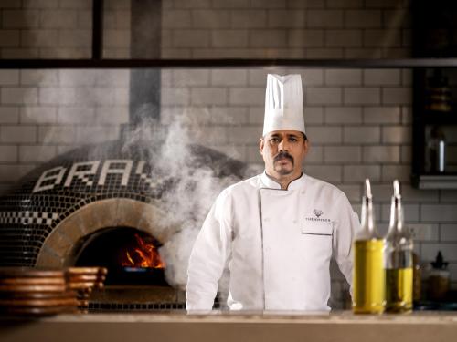 a chef standing in front of a pizza oven at The Khyber Himalayan Resort & Spa in Gulmarg