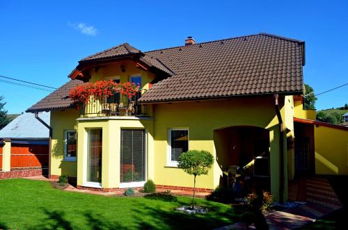 una casa amarilla con un balcón con flores. en Vila Deluxe & Apartmány Riviéra Liptov Bešeňová, en Bešeňová