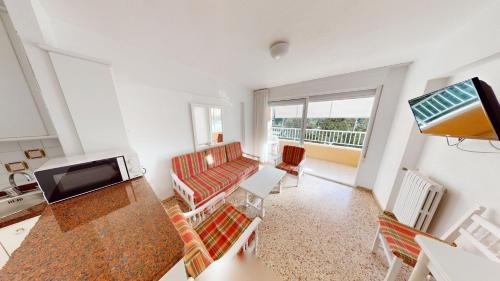 Una sala de estar con un sofá y un televisor. en Apartamentos Concorde, en Alicante
