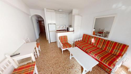 Una sala de estar con un sofá y una cocina. en Apartamentos Concorde, en Alicante